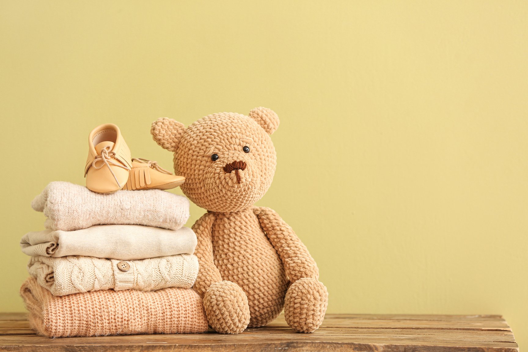 Stack of Baby Clothes and Toy on Table